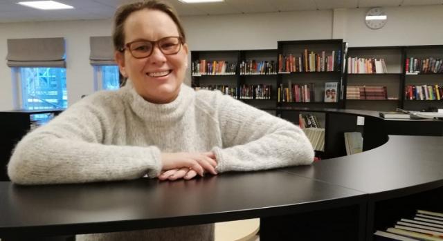 Modersmålsläraren Camilla Nygård vid en hylla i ett bibliotek.